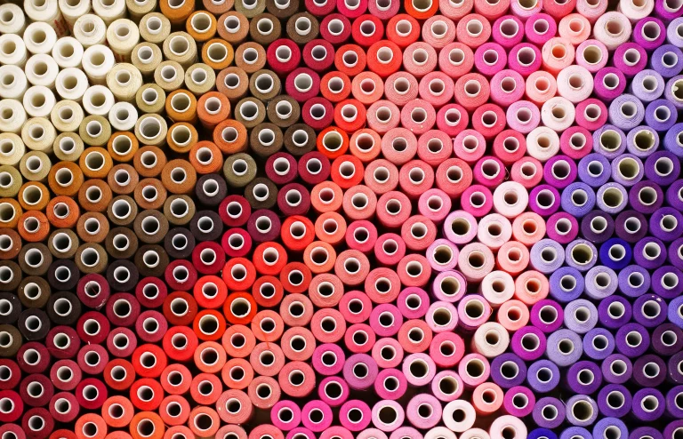 Bunte Nähgarnspulen – empfindliches Schüttgut für präzise Fördertechnik in der Textilindustrie von JOEST.
