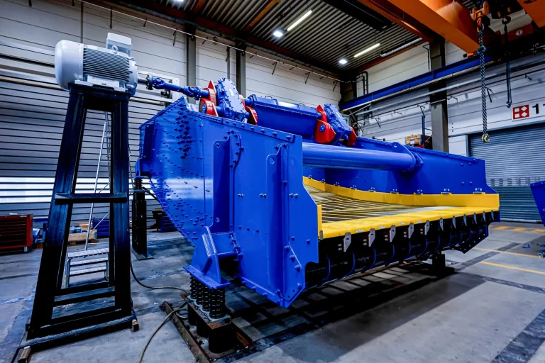 Großes blau-gelbes Linearschwingsieb von JOEST für den Bergbau, installiert in einer Produktionshalle.