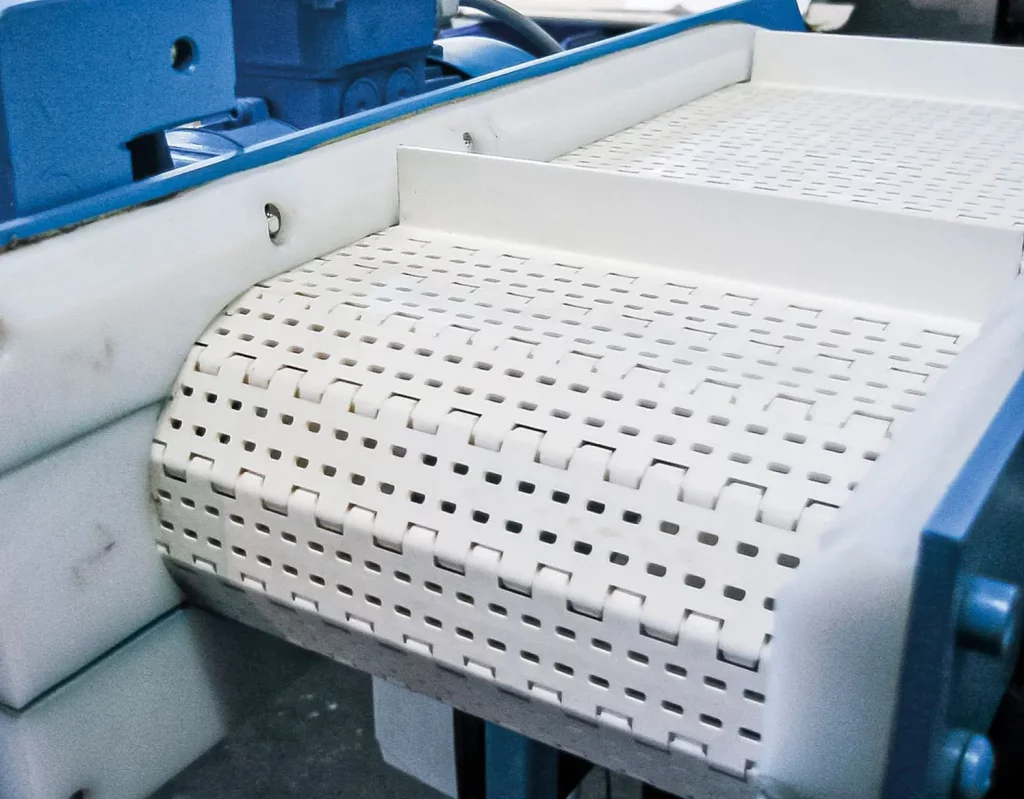 Nahaufnahme gelochter Kunststoff-Scharnierglieder eines Scharniergurtförderers.