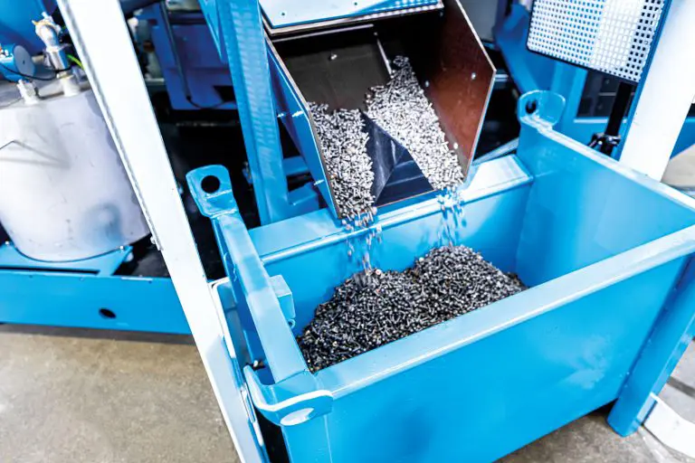 Gereinigte Massenkleinteile werden aus einer Waschzentrifuge in ein Behälter gekippt.