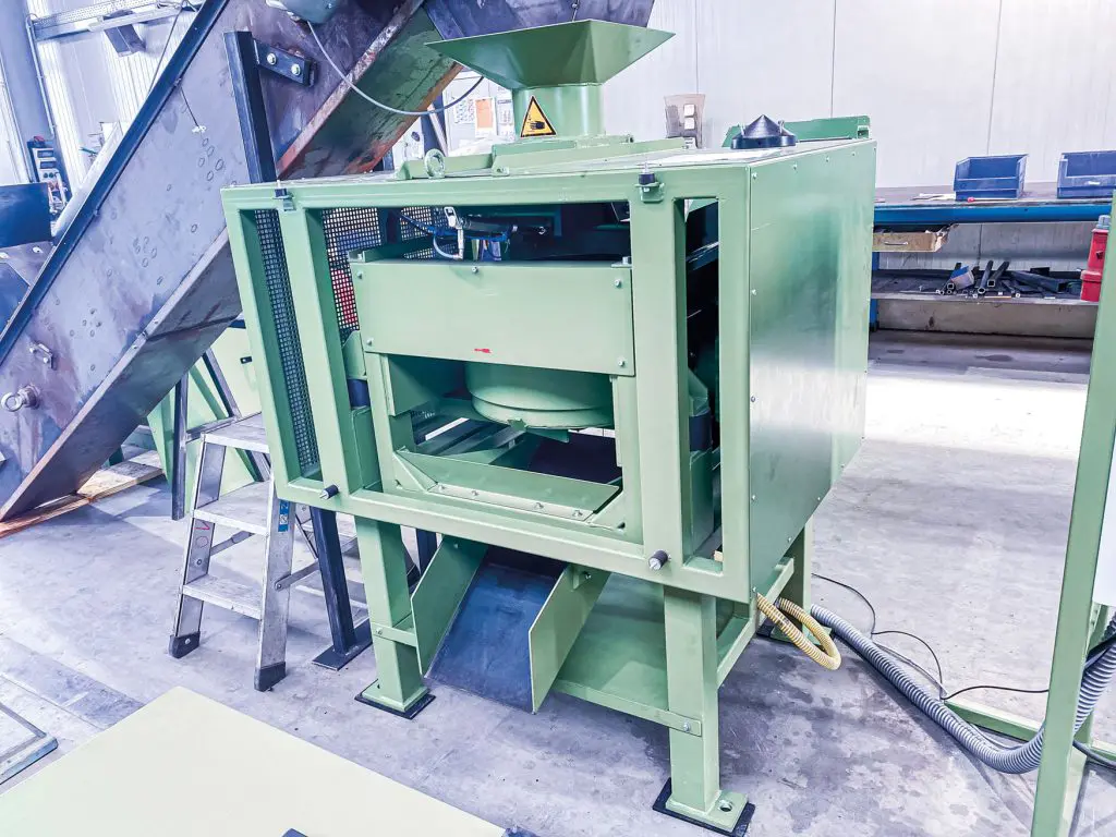 Green industrial de-oiling centrifuge for cleaning metallic workpieces.