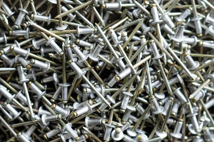 Close-up of cleaned metal blind rivets after the cleaning and de-oiling process in an industrial washing centrifuge.