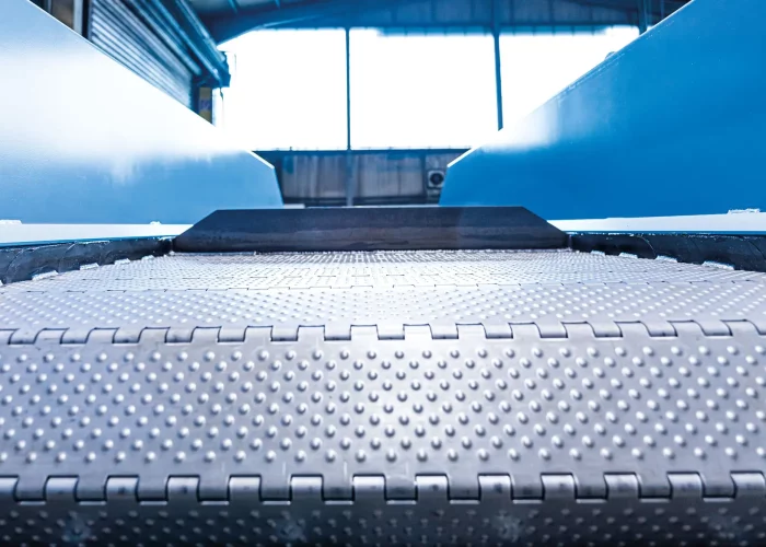 Gestanzte Scharnierglieder mit Mitnehmern auf einem Scharniergurtförderer