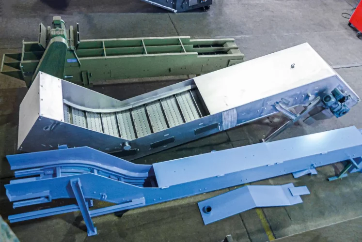 Immersion bath conveyor with robust conveyor belt and curved routing in a factory hall