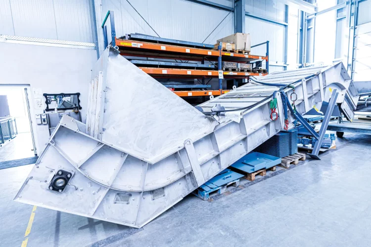 Tauchbadförderer mit gebogener Linienführung in industrieller Werkhalle.