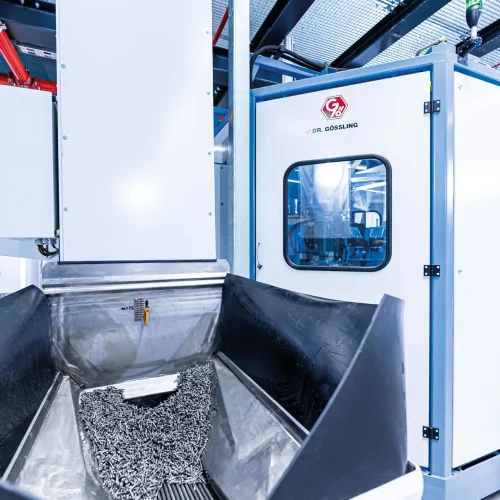 Austragsbereich einer industriellen Waschzentrifuge mit gereinigten Metallteilen nach dem Reinigungs- und Entölungsprozess.