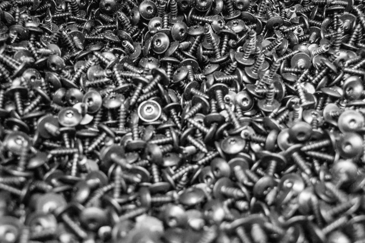 Close-up of metal screws after cleaning and de-oiling in an industrial washing centrifuge.